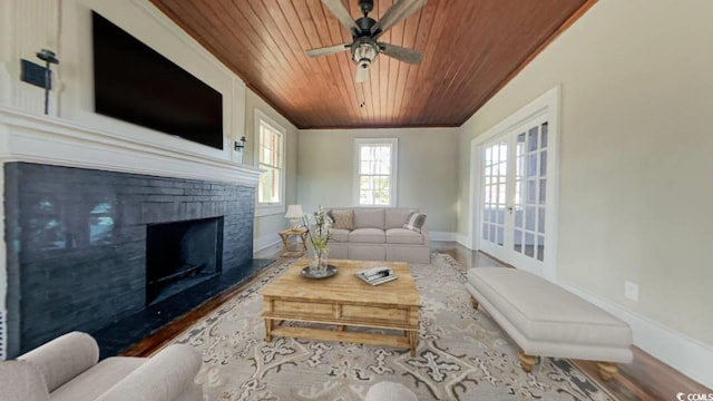 living room featuring ceiling fan, a brick fireplace, ornamental molding, wood ceiling, and hardwood / wood-style flooring