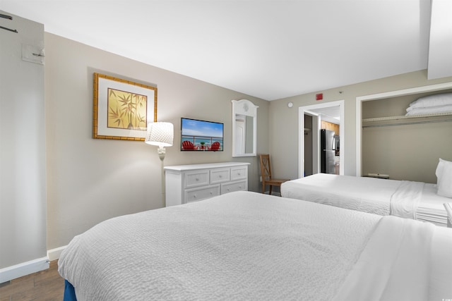 bedroom with black refrigerator, hardwood / wood-style flooring, and a closet