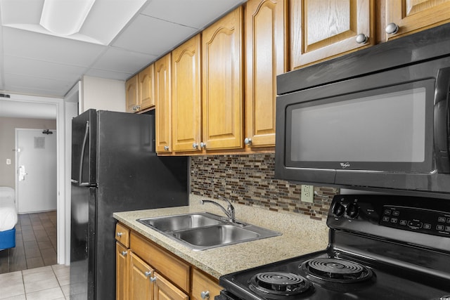 kitchen featuring sink, a drop ceiling, decorative backsplash, light tile patterned floors, and black appliances