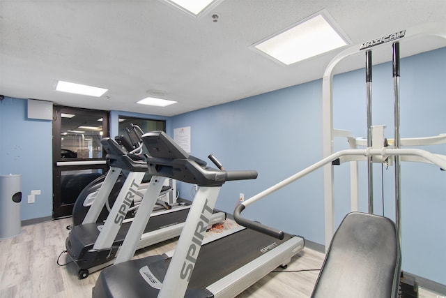 workout area with light hardwood / wood-style floors and a textured ceiling