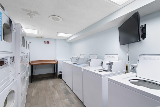 laundry room with washer and clothes dryer, a textured ceiling, stacked washer / dryer, and light hardwood / wood-style flooring