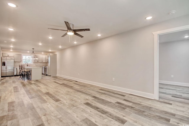 unfurnished living room with ceiling fan, light hardwood / wood-style floors, and sink