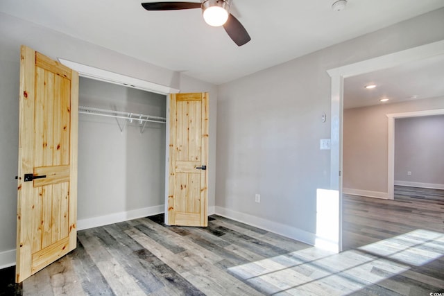 unfurnished bedroom featuring ceiling fan, wood-type flooring, and a closet