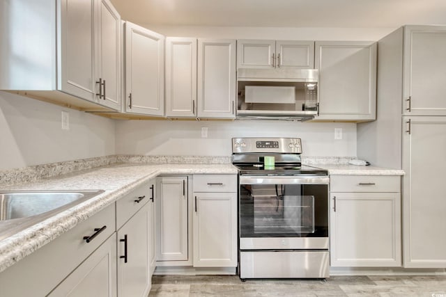 kitchen featuring light stone countertops, stainless steel appliances, and light hardwood / wood-style flooring