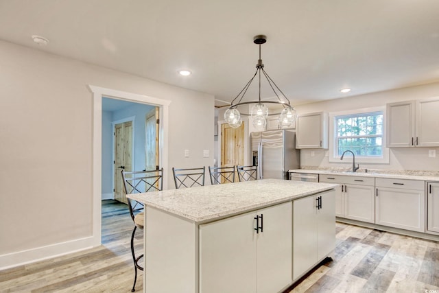 kitchen featuring a kitchen breakfast bar, stainless steel appliances, light hardwood / wood-style flooring, white cabinets, and a kitchen island