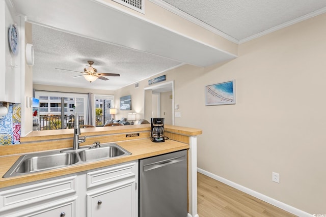 kitchen with white cabinetry, sink, stainless steel dishwasher, light hardwood / wood-style floors, and a textured ceiling