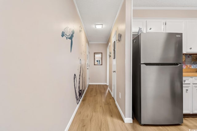 hallway featuring a textured ceiling, light hardwood / wood-style flooring, and ornamental molding