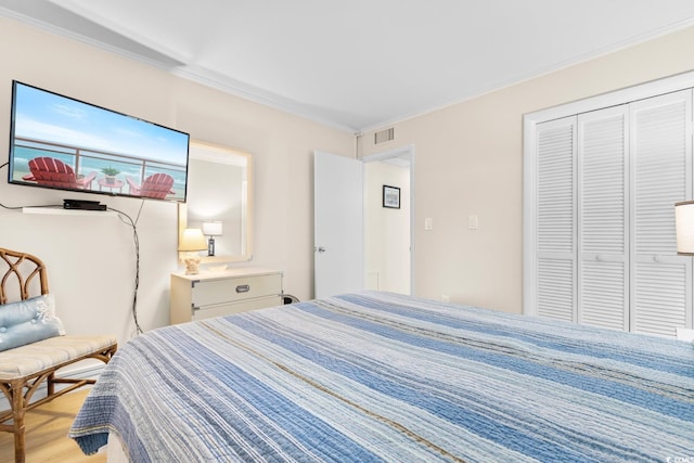 bedroom with light hardwood / wood-style floors, crown molding, and a closet