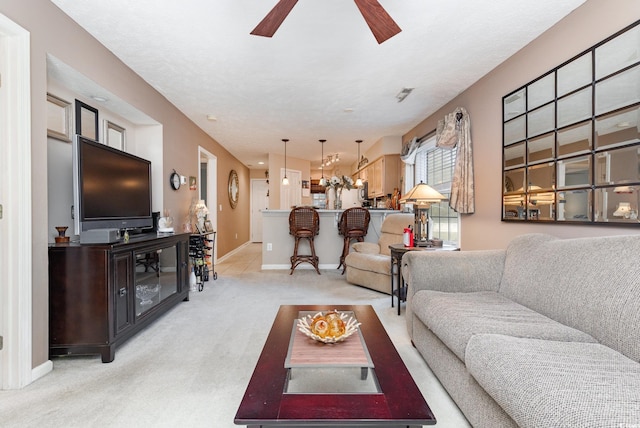 living room with ceiling fan, light colored carpet, and a textured ceiling