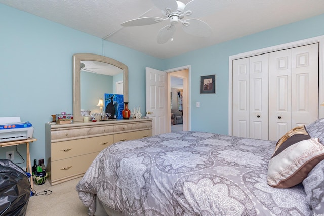 bedroom with ceiling fan, light colored carpet, a textured ceiling, and a closet