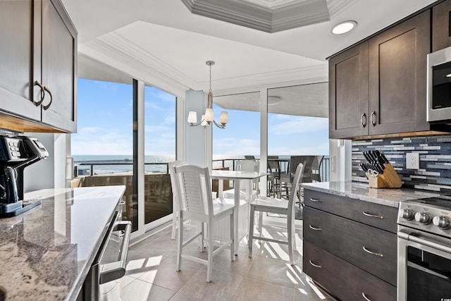 kitchen featuring stainless steel appliances, a water view, dark brown cabinets, and light stone counters