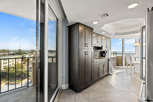 kitchen with dark brown cabinetry, sink, crown molding, stainless steel dishwasher, and a tray ceiling