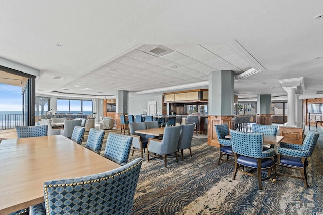 carpeted dining space featuring a water view and ornate columns