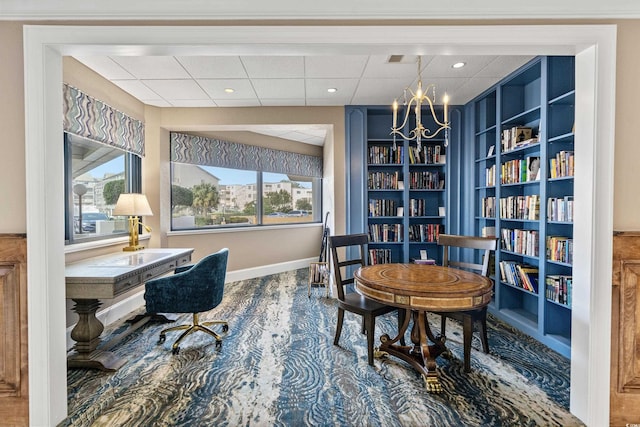 office with a paneled ceiling, a chandelier, and built in shelves