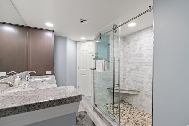 bathroom with an enclosed shower, vanity, and wood-type flooring