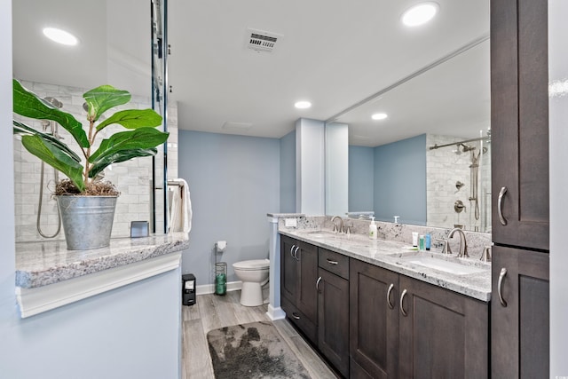 bathroom featuring tiled shower, wood-type flooring, toilet, and vanity