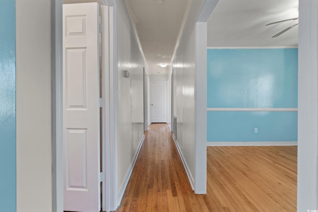 hall featuring crown molding, a textured ceiling, and hardwood / wood-style flooring