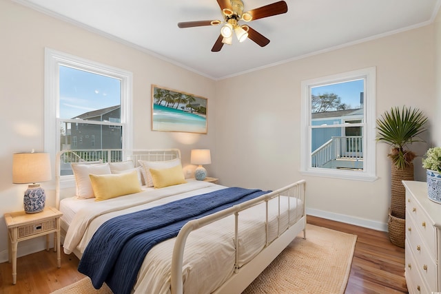 bedroom with ceiling fan, crown molding, multiple windows, and light hardwood / wood-style flooring