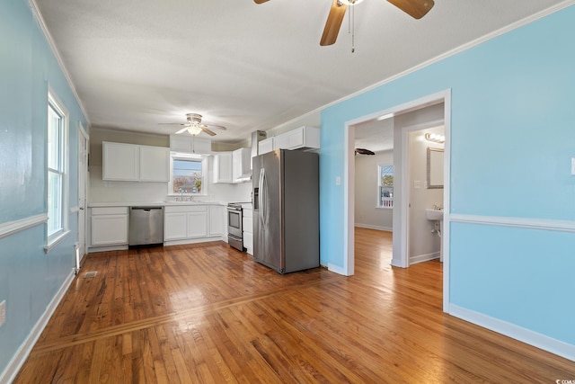 kitchen with white cabinets, sink, stainless steel appliances, and hardwood / wood-style floors