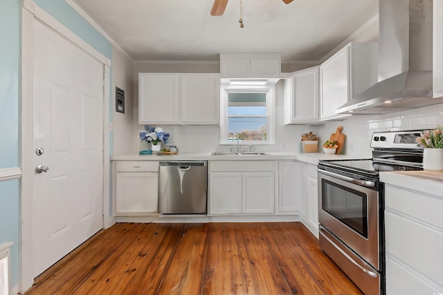 kitchen featuring sink, white cabinetry, appliances with stainless steel finishes, and wall chimney exhaust hood