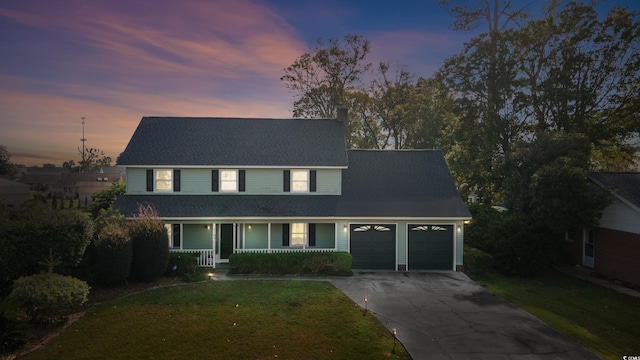 view of front facade featuring a yard, covered porch, and a garage