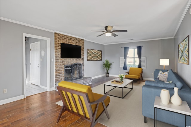 living room with a fireplace, wood-type flooring, ceiling fan, and crown molding