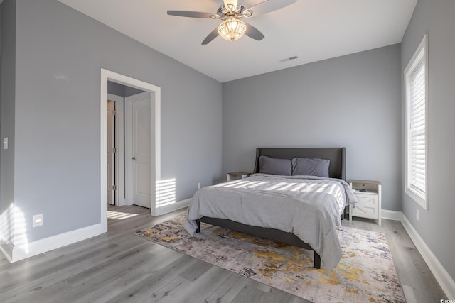 bedroom with multiple windows, ceiling fan, and light wood-type flooring