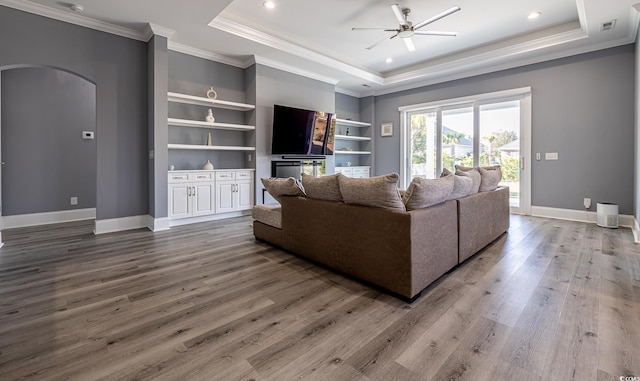 living room featuring hardwood / wood-style flooring, ceiling fan, and a tray ceiling