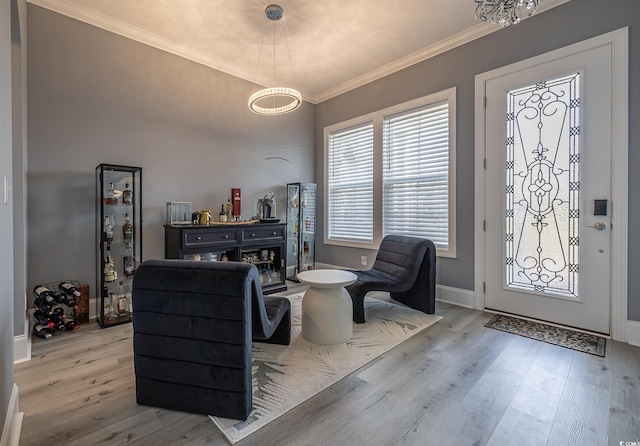 foyer entrance with light hardwood / wood-style flooring, ornamental molding, and a notable chandelier