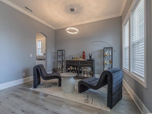 living area featuring hardwood / wood-style flooring, plenty of natural light, and crown molding