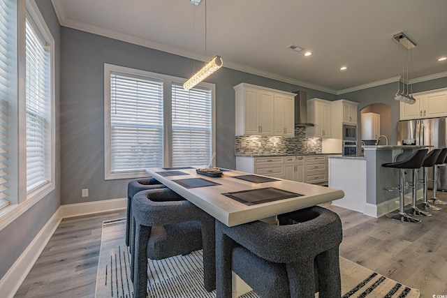 dining area featuring light hardwood / wood-style flooring and ornamental molding