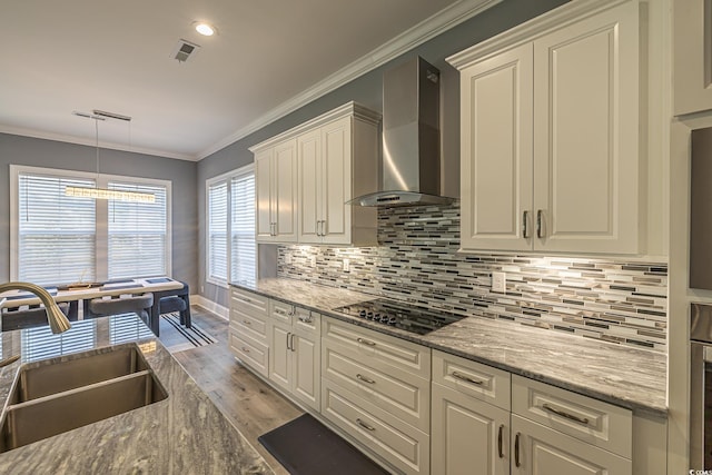 kitchen featuring crown molding, sink, wall chimney exhaust hood, black electric cooktop, and light hardwood / wood-style floors