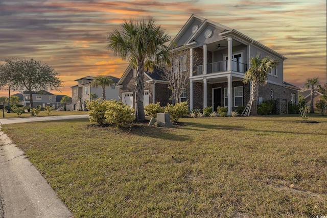 view of front of property featuring a garage, a balcony, and a yard