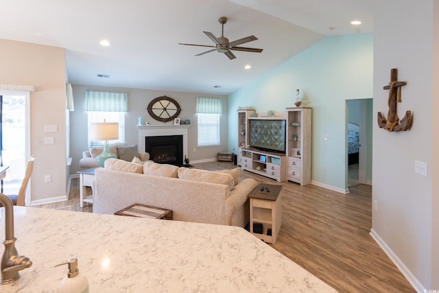 living room with light wood-type flooring, plenty of natural light, lofted ceiling, and ceiling fan