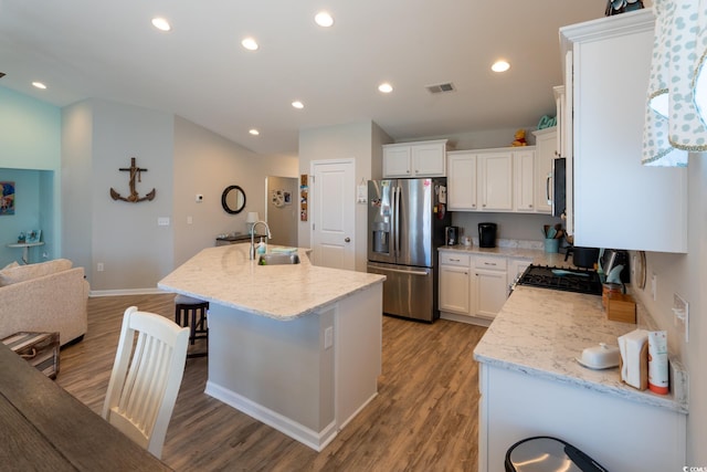 kitchen featuring appliances with stainless steel finishes, light stone counters, a kitchen island with sink, sink, and light hardwood / wood-style flooring