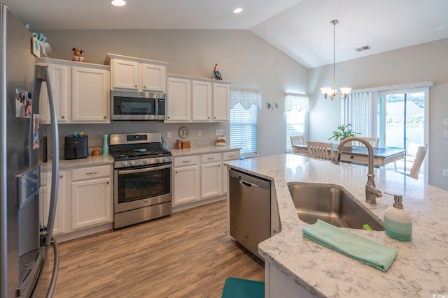 kitchen with lofted ceiling, sink, white cabinetry, and stainless steel appliances