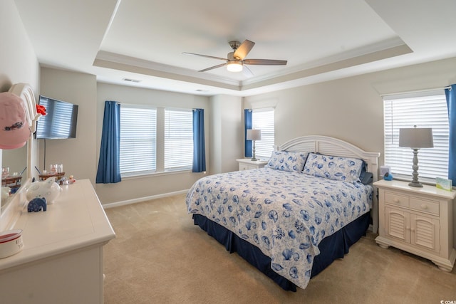 carpeted bedroom with a tray ceiling, ceiling fan, and ornamental molding