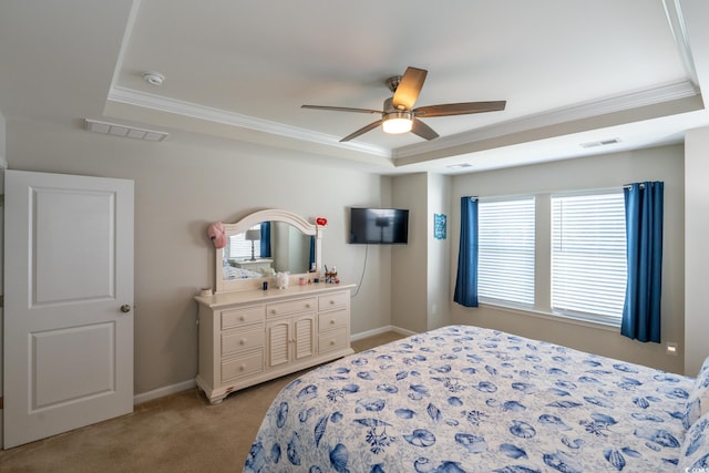 carpeted bedroom with a raised ceiling, multiple windows, ceiling fan, and ornamental molding