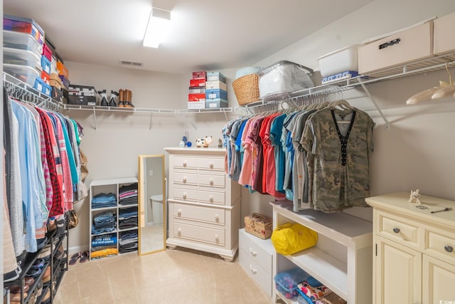 walk in closet with light carpet