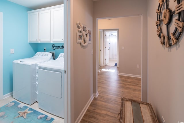 laundry area with washer and dryer, cabinets, and light wood-type flooring