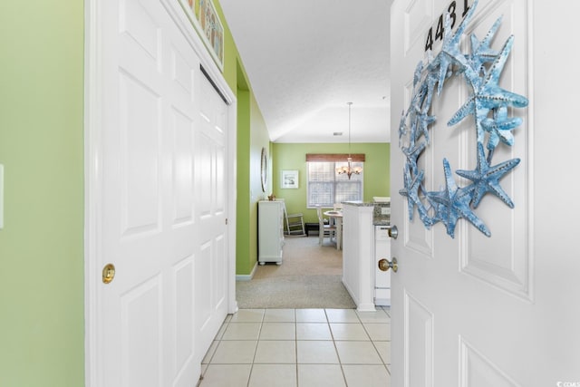 hallway featuring a notable chandelier, light tile patterned floors, and a textured ceiling