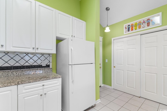 kitchen with tasteful backsplash, dark stone counters, white refrigerator, decorative light fixtures, and white cabinetry