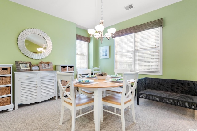 dining area with light colored carpet and a chandelier