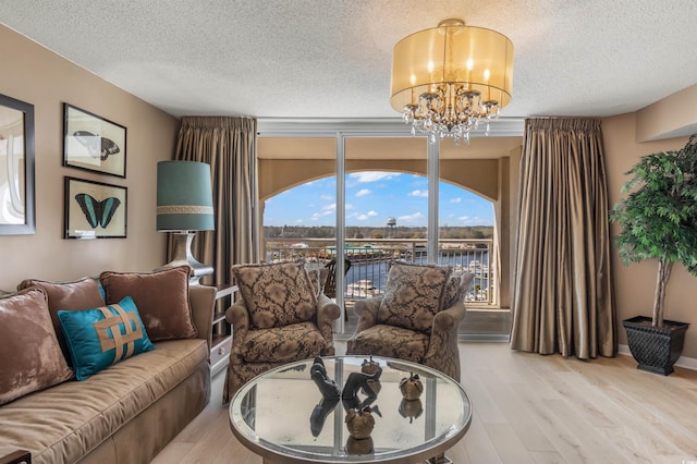 living room with hardwood / wood-style floors, a textured ceiling, a water view, and an inviting chandelier