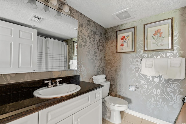 bathroom featuring tile patterned flooring, vanity, toilet, and a textured ceiling