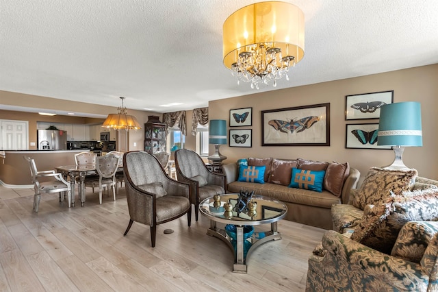 living room with a notable chandelier, light wood-type flooring, and a textured ceiling