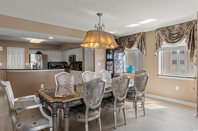 dining area with a textured ceiling and light wood-type flooring