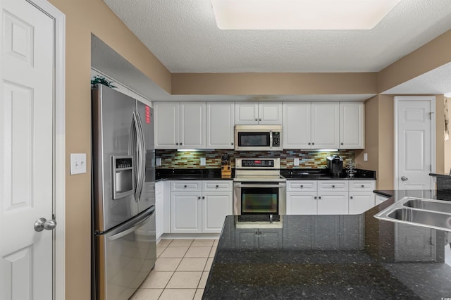 kitchen featuring white cabinets, light tile patterned floors, a textured ceiling, and stainless steel appliances