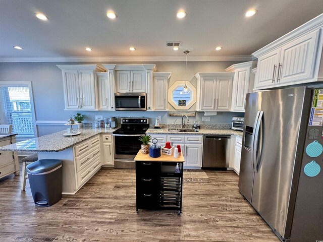 kitchen featuring sink, a center island, hanging light fixtures, white cabinets, and appliances with stainless steel finishes