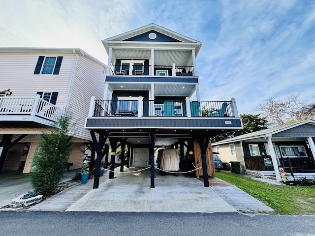 raised beach house featuring a balcony and a carport